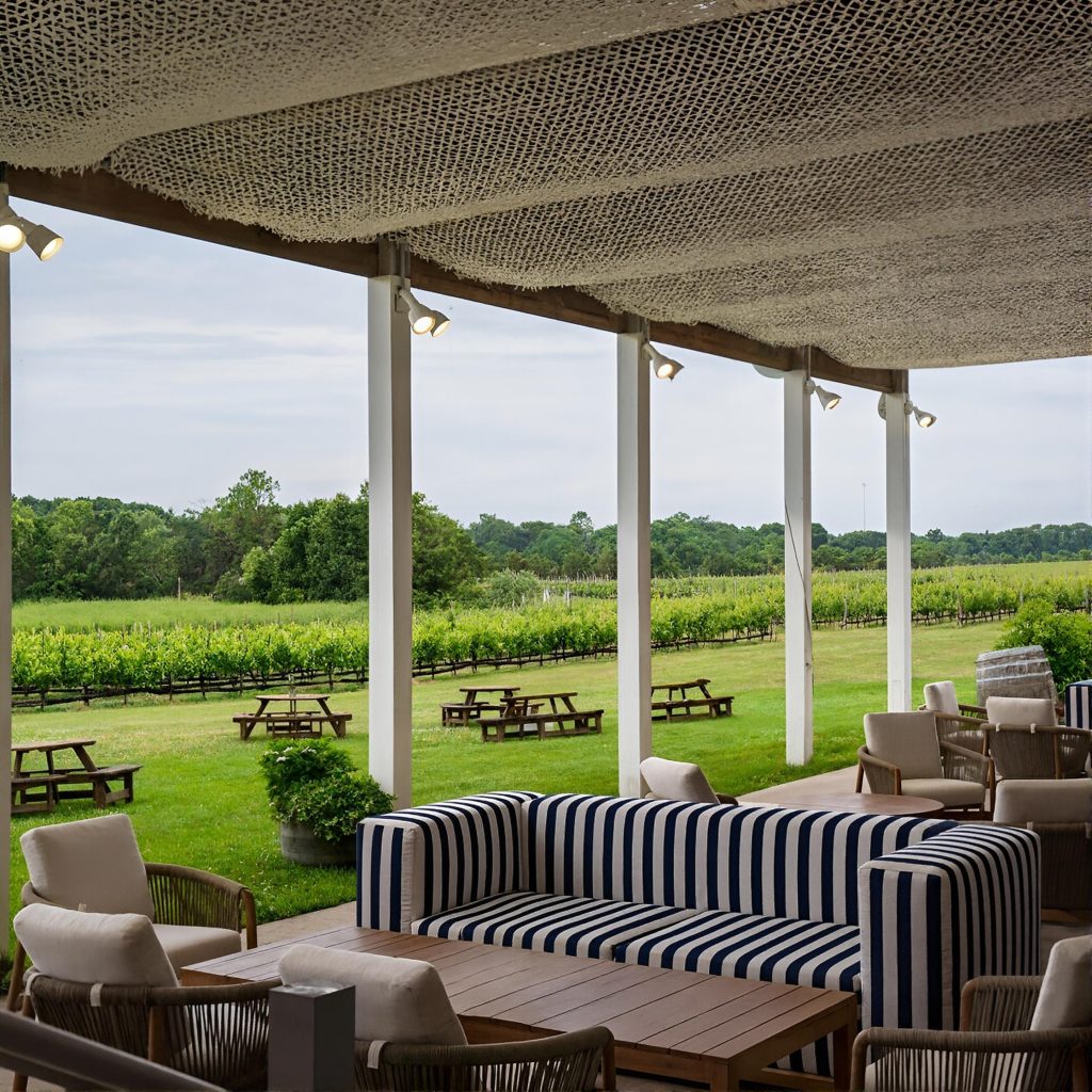 Vineyard view of the deck at Ev&Em Vineyards with lounge-style seating, couches, and tables on the North Fork of Long Island during a Long Island wine tour.