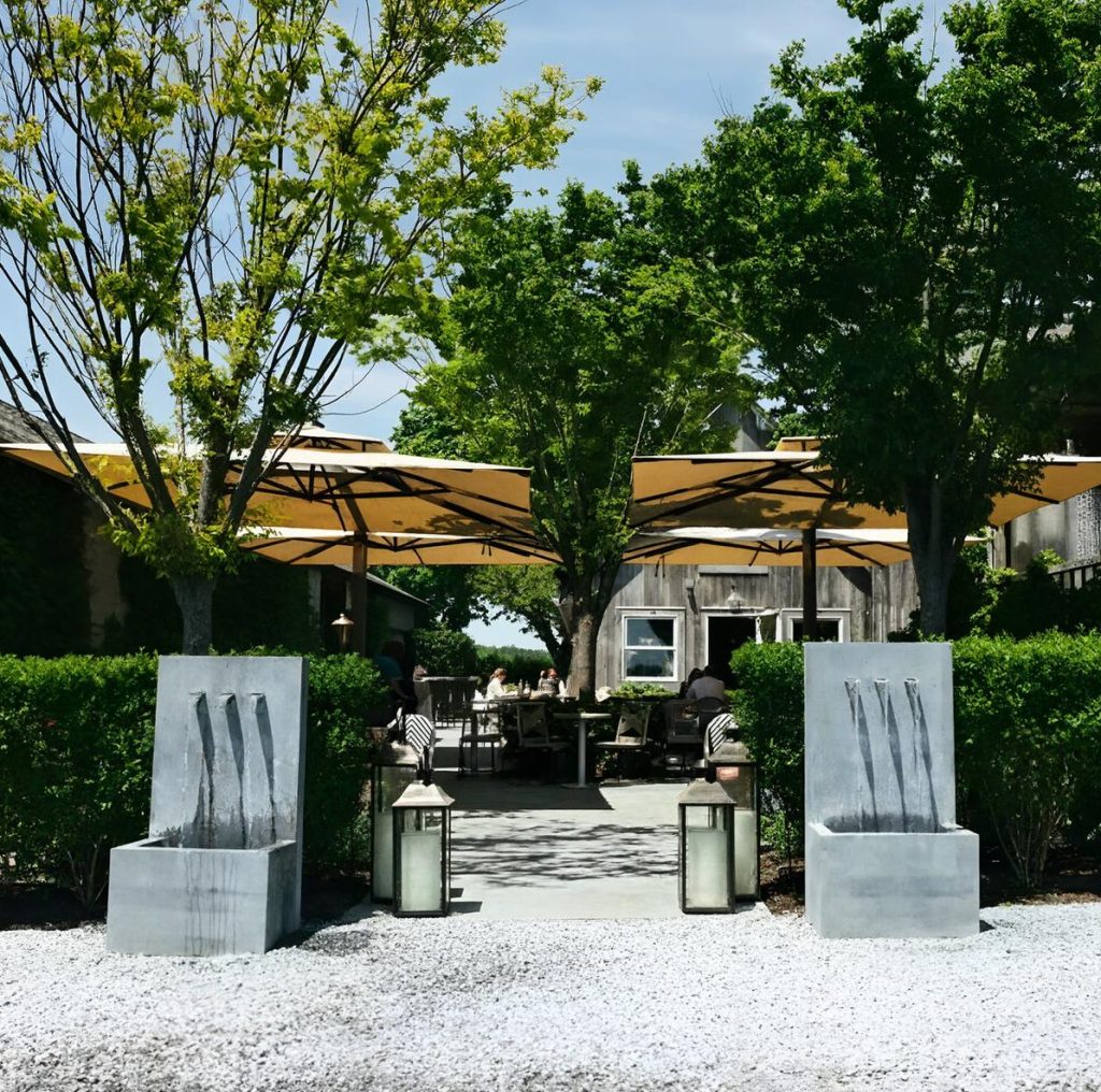 Wine tasting garden at Rose Hill Vineyards & Inn on the North Fork of Long Island with outdoor tables and umbrellas during a private chauffeured wine tour.