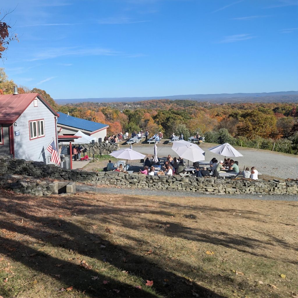 Outdoor picnic area with tables and umbrellas at Quartz Rock Vineyard in the Hudson Valley during a chauffeured wine tasting tour from New York City.